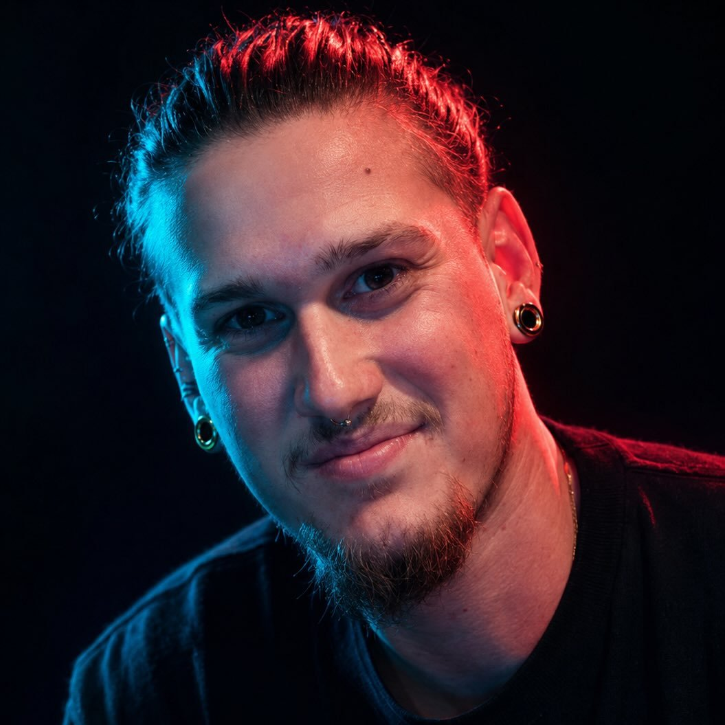 Portrait of tattoo artist Osiel lit in red and blue studio light